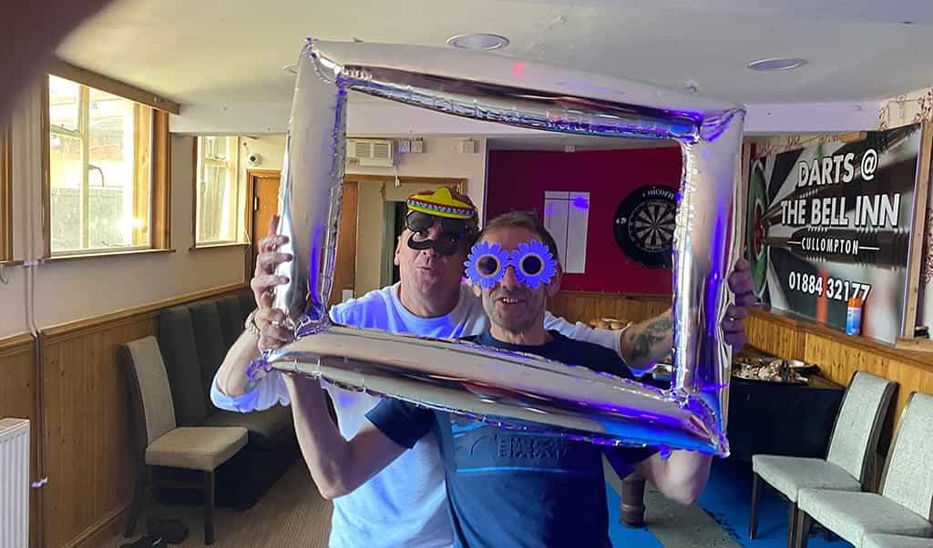 Ryan's Dad, Nigel and Dave wearing funny faces behind a blow-up picture frame